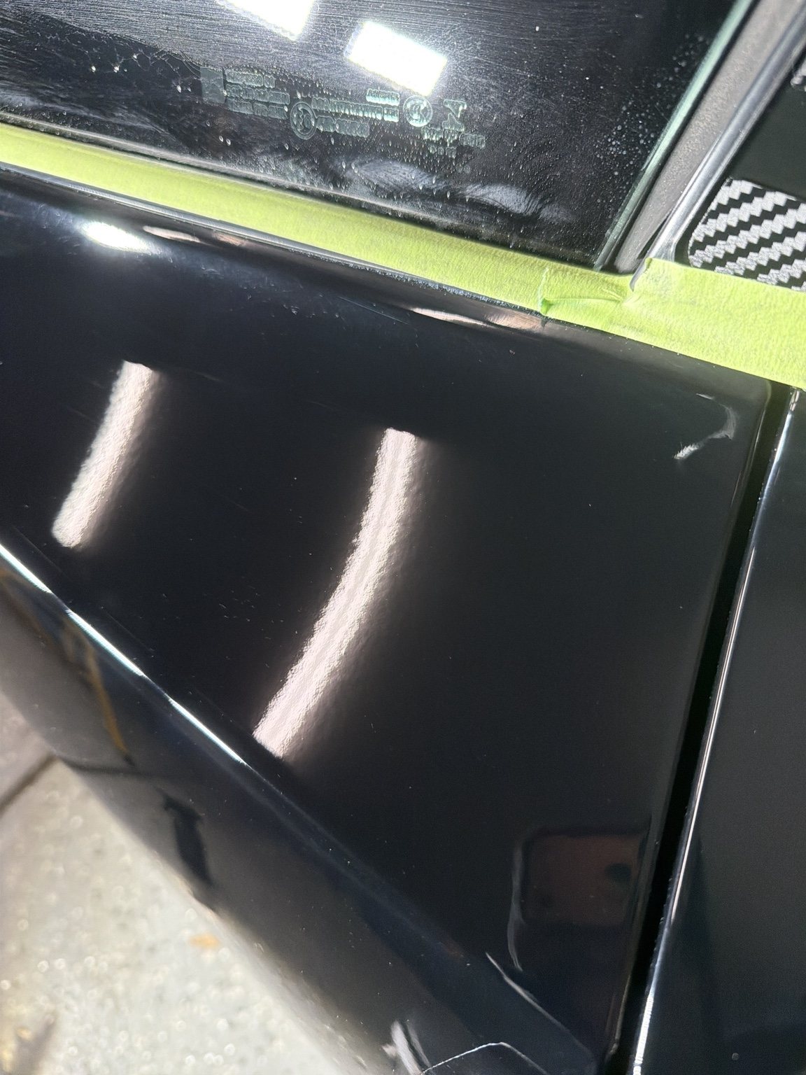 Close view of a polished black door panel after paint correction